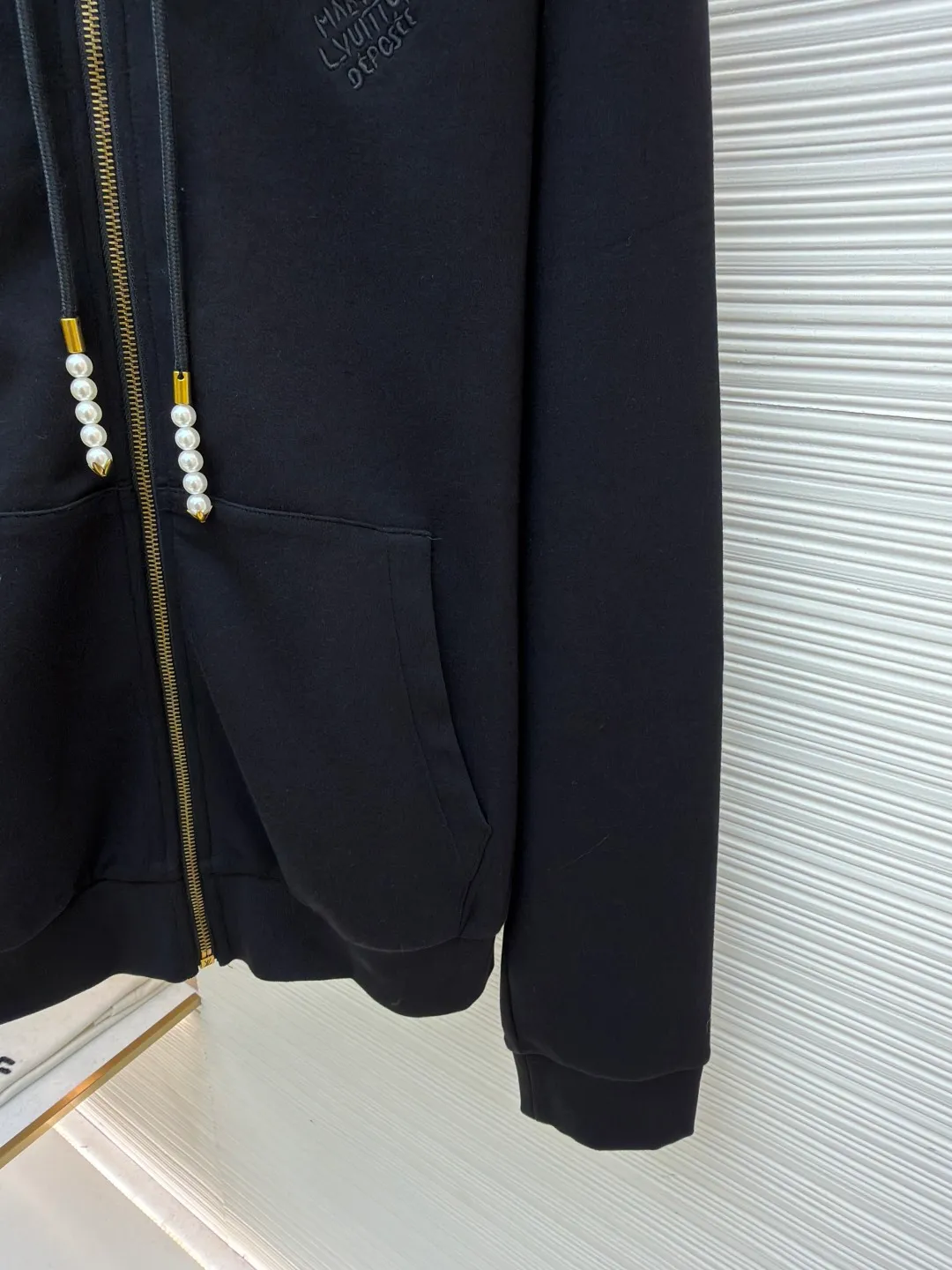 LOUIS VUITTON Pearl Pendant Zipper Jacket ●Original version: Purchased and developed for 10999 ●Item number: 1682253-B60 ●Fabric: wool blended fabric ●Technology: knitted embroidery production ●Color: black ●Version: fitted version ●Weight: about 715 grams ●Size: S-M-L-XL ●Description: This Louis Vuitton black hooded zipper sweatshirt is made of high-weight pure cotton waffle fabric. The fabric has been combed and singed, with a uniform and fine surface texture. It is also treated with anti-pilling and pre-shrunk, making it soft to the touch and not easily deformed after long-term wear. The brand logo on the left side of the body adopts the same color dark pattern embossing process and is hot-pressed through a temperature-controlled mold. The pattern is low-key and has a strong three-dimensional effect. The drawstring is embellished with custom-made pearl decorations, which are fixed by hand-beading. The surface of the pearls is polished to have a good luster and will not fall off easily. The metal zipper is made of gold-plated brass and has been treated with antioxidant treatment. The chain head is engraved with the brand's classic logo, making it smooth and wear-resistant. The ribs on the cuffs and hem are made of spandex blended material, which has excellent resilience and is not easy to loosen. The overall design is cut with loose shoulders, combined with double-needle hemming and seamless splicing technology. The stitching is fine and flat, which not only ensures comfort, but also shows the exquisite craftsmanship and brand texture of high-end garments. The overall wiring is straight and delicate, the fabric is comfortable and soft, and the color is consistent without color difference. It can be matched with the same style to create a fashionable look and control various occasions. Customized accessories, complete with three standards, same style for men and women!
